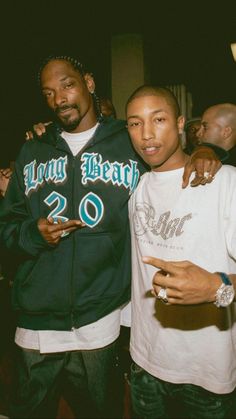 two young men standing next to each other in front of a crowd at a party