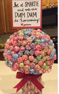 a vase filled with lots of candy sitting on top of a counter next to a sign