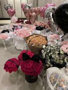 a table filled with lots of pink and white flowers next to heart shaped helium balloons