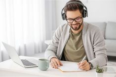 a man wearing headphones sitting at a desk with a notebook and pen