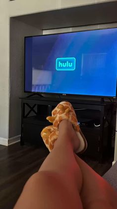 a person is laying down in front of a tv with their feet propped up on the television