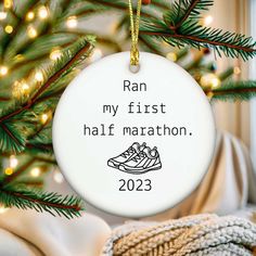 a white ornament hanging from a christmas tree that says ran my first half marathon