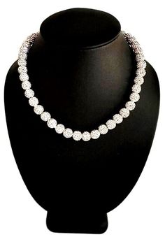 a necklace on a black mannequin with white stones in the shape of circles