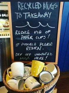 a basket filled with coffee cups sitting on top of a table next to a chalk board