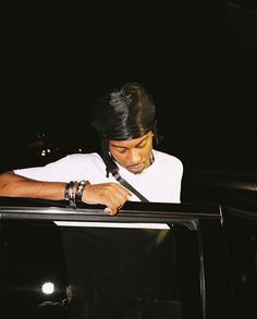 a man in white shirt and black tie leaning out the window of a car at night