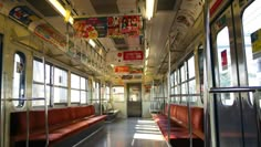 an empty subway car with red seats and posters on the wall above it's windows