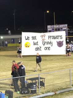 a group of people standing on top of a baseball field next to a sign that reads, we got 99 problems but grundy ain't one