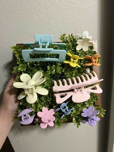 a person holding up a plant with flowers and clips on it