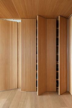 an empty room with wooden partitions and shelves in the corner, as well as wood flooring