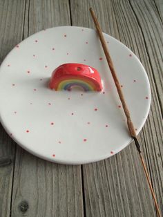 a small red object on a white plate with a wooden stick in the middle of it