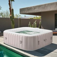 an inflatable hot tub sitting on top of a pool next to a cactus