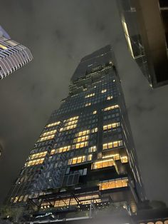 a very tall building with lots of windows at the top and lights lit up on it's sides