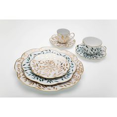 a set of four plates and cups with leaves on them, sitting next to each other