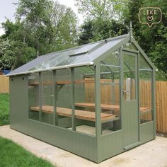 a wooden bench sitting in the middle of a small green house next to a fence