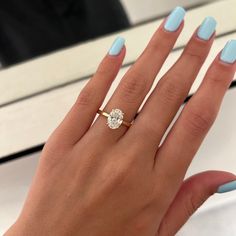 a woman's hand with blue nail polish and a diamond ring on her finger