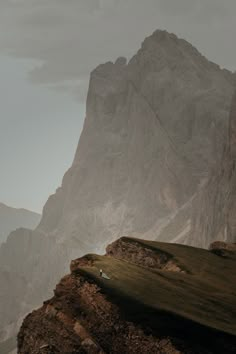 a person standing on the side of a mountain with a surfboard in their hand