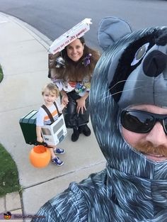 a man in a bear costume and two children on the sidewalk with an orange ball