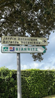 a street sign in front of a hedge and tree with the name bariritz on it