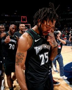 a man with dreadlocks standing in front of a basketball court while holding his hand to his mouth