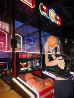 a woman is playing basketball in an arcade