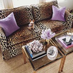 a living room with leopard print couches and purple pillows on top of the couch