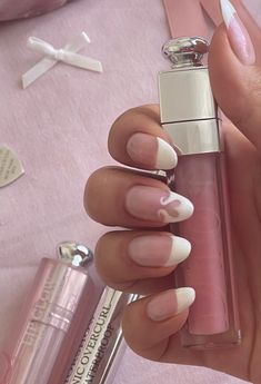 White french tip nails with heart detail, hand posed holding onto a Dior lipgloss Pink Pilates Nails, Nails Almond Coquette, Dollete Nails, Couqutte Nails, Ballet Core Nails, Pink Nails Coquette, Heart French Nails, Heart French Tip Nails, Coquette Nail Ideas