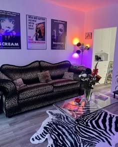 a living room with zebra print furniture and posters on the wall above it's glass coffee table