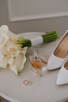 the bride's bouquet and shoes are on the table next to the perfume bottle