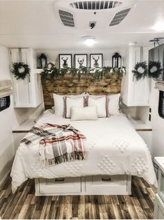 a white bed sitting inside of a bedroom next to a wooden headboard with wreaths on it