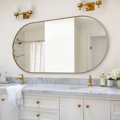 a white bathroom with marble counter tops and gold faucets on the sink vanity