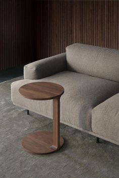 a couch with a wooden table in front of it on the floor next to a wall