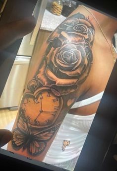 a woman's arm with a clock and rose tattoo on it