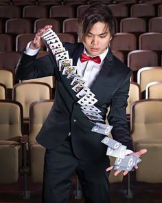 a man in a tuxedo is holding up some cards with words on them