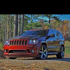 a red jeep is parked in the woods