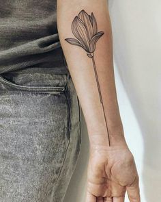 a woman's arm with a single flower tattoo on the left side of her hand