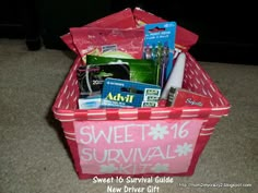 a pink box filled with lots of items on top of a carpeted floor next to a black wall