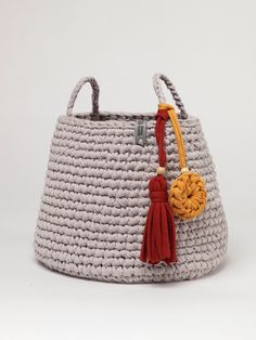 a crocheted basket with tassels and a yellow ball hanging from the handle