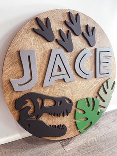 a wooden sign that says jace with dinosaurs and palm leaves