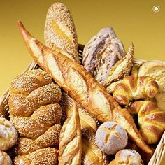 a basket filled with lots of different types of breads and pastries on top of a table