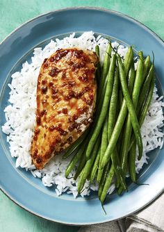 a blue plate topped with green beans and chicken next to rice on top of a table