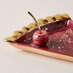 an apple is sitting on top of a red and gold serving tray with a golden handle