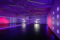 an empty room with purple lighting and white circles on the wall