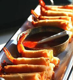 hotdogs with ketchup and mustard on a white plate next to a spoon