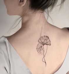 a woman's back neck with a flower tattoo on the left side of her neck