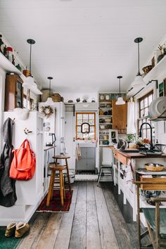 a kitchen filled with lots of wooden floors and white walls next to an open window