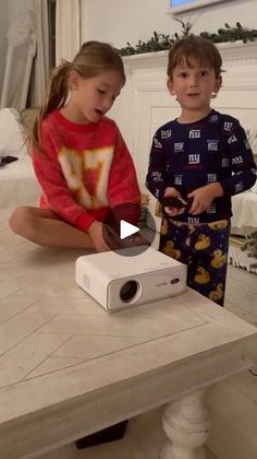 two young children sitting on the floor playing with a projector in front of them