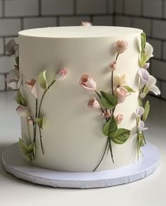 a white cake decorated with flowers and leaves