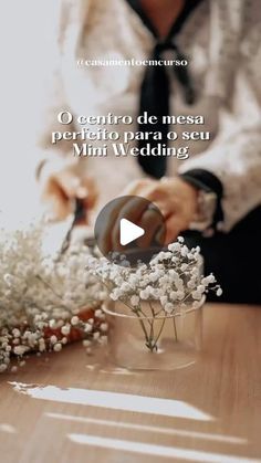 a person cutting flowers with scissors on a wooden table in front of a vase filled with baby's breath