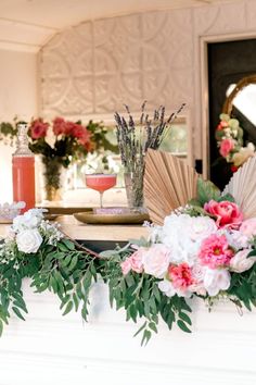 flowers and greenery are arranged on the mantel