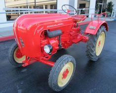 an old red tractor parked in front of a building